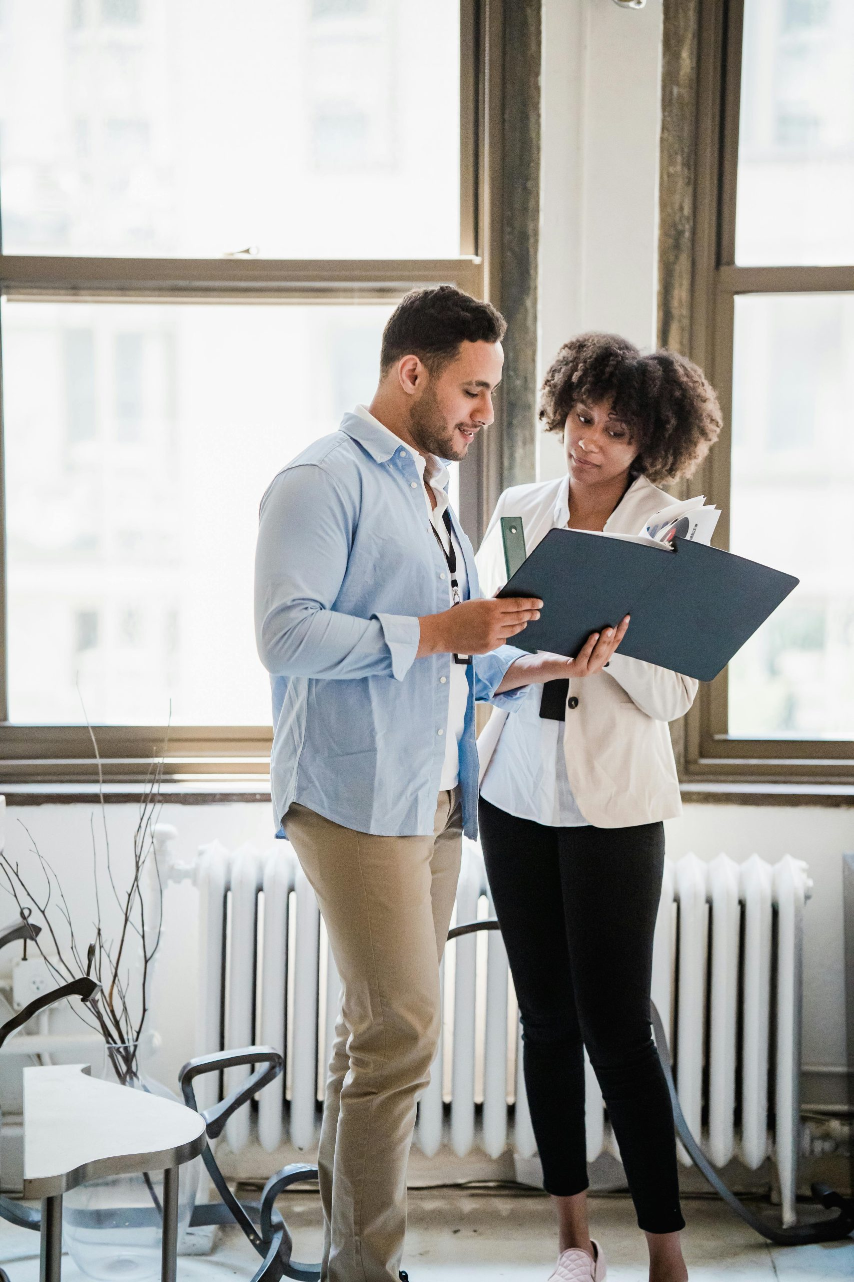 A young man and woman reviewing documents in a bright office setting.